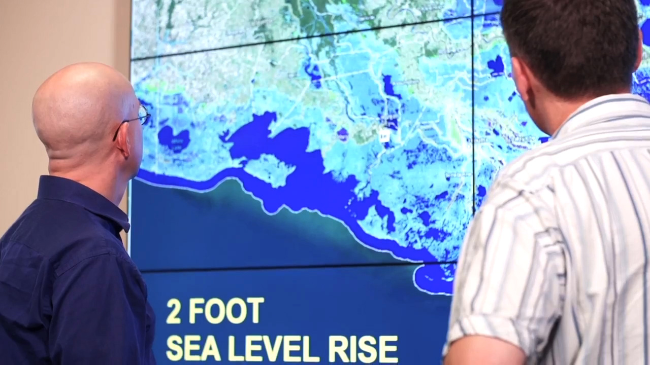 scientists looking at digital model of sea level projections