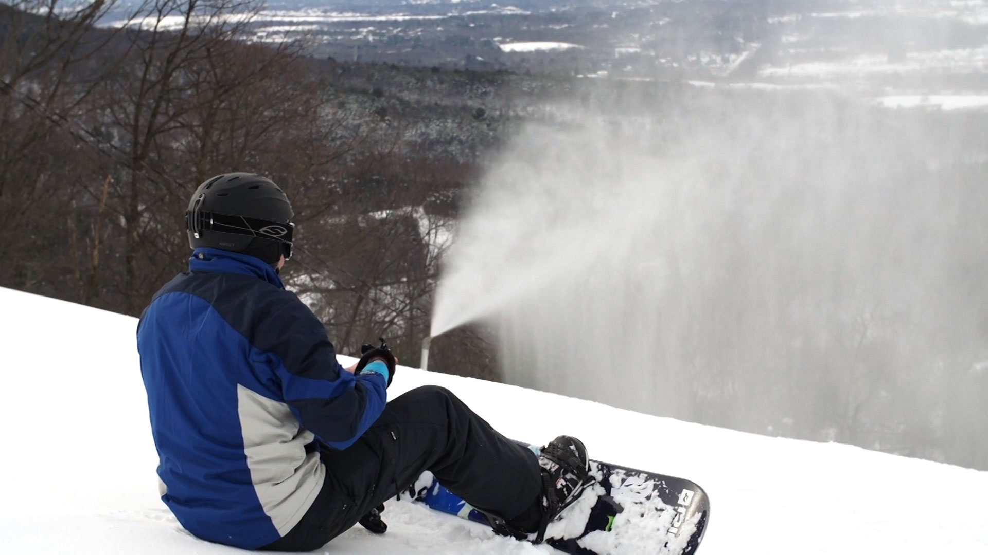 snow boarder sitting down at top of ski slope
