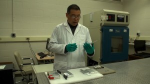 Scientist in lab with lithium battery in hand.