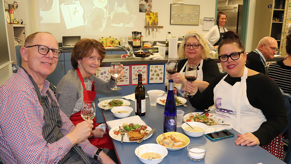 guests at dinner table holding wine glasses for a toast