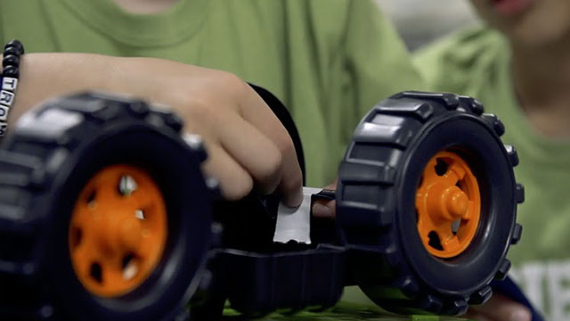 person repairing axel of toy truck