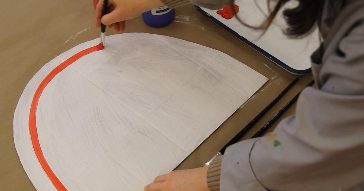 A person painting a red stripe on a rainbow