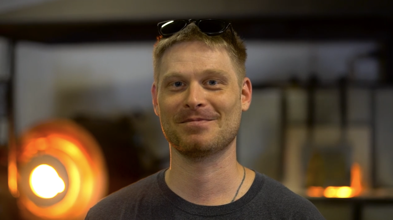 A man standing in front of a glass furnace