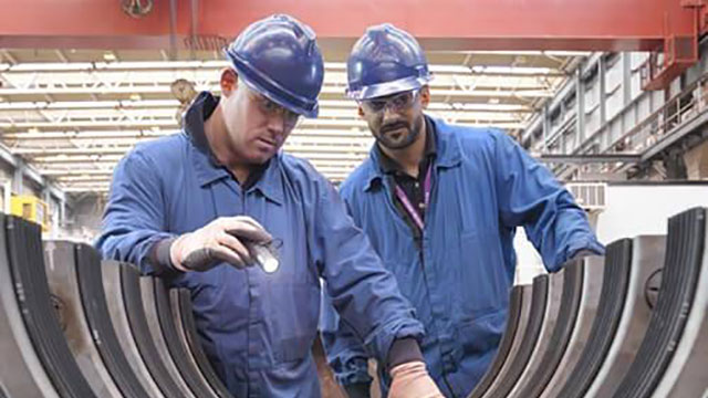engineers shining flashlight on machinery