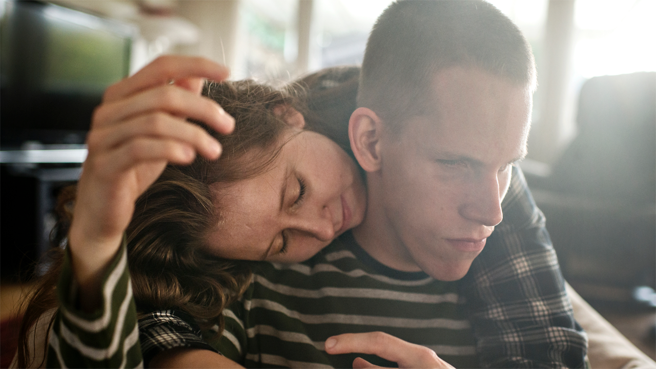 A boy being hugged by his sister.