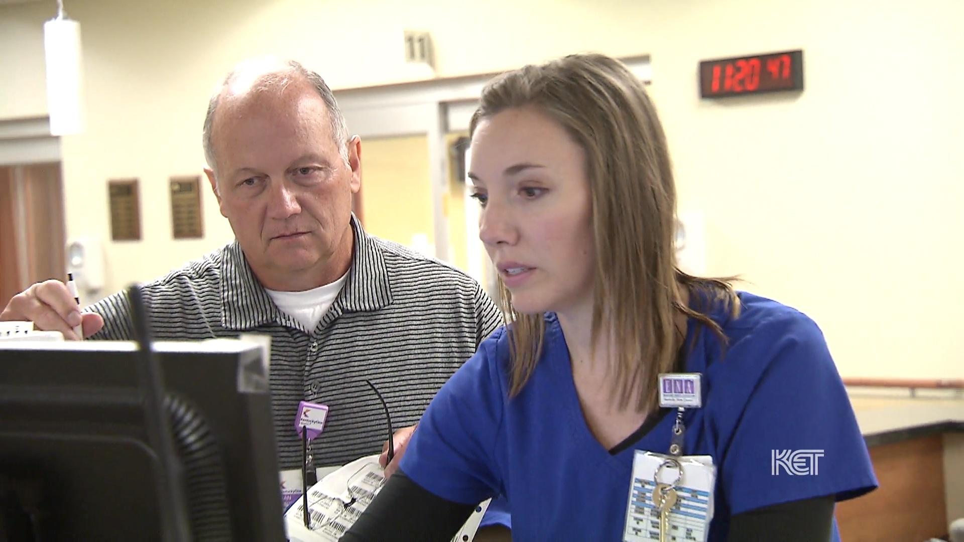 A woman and man looking at a computer monitor.