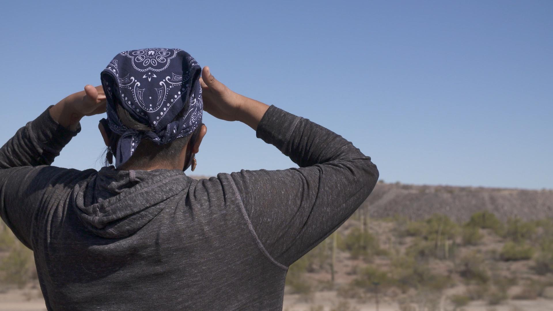 A person looking away from the camera out across a desert