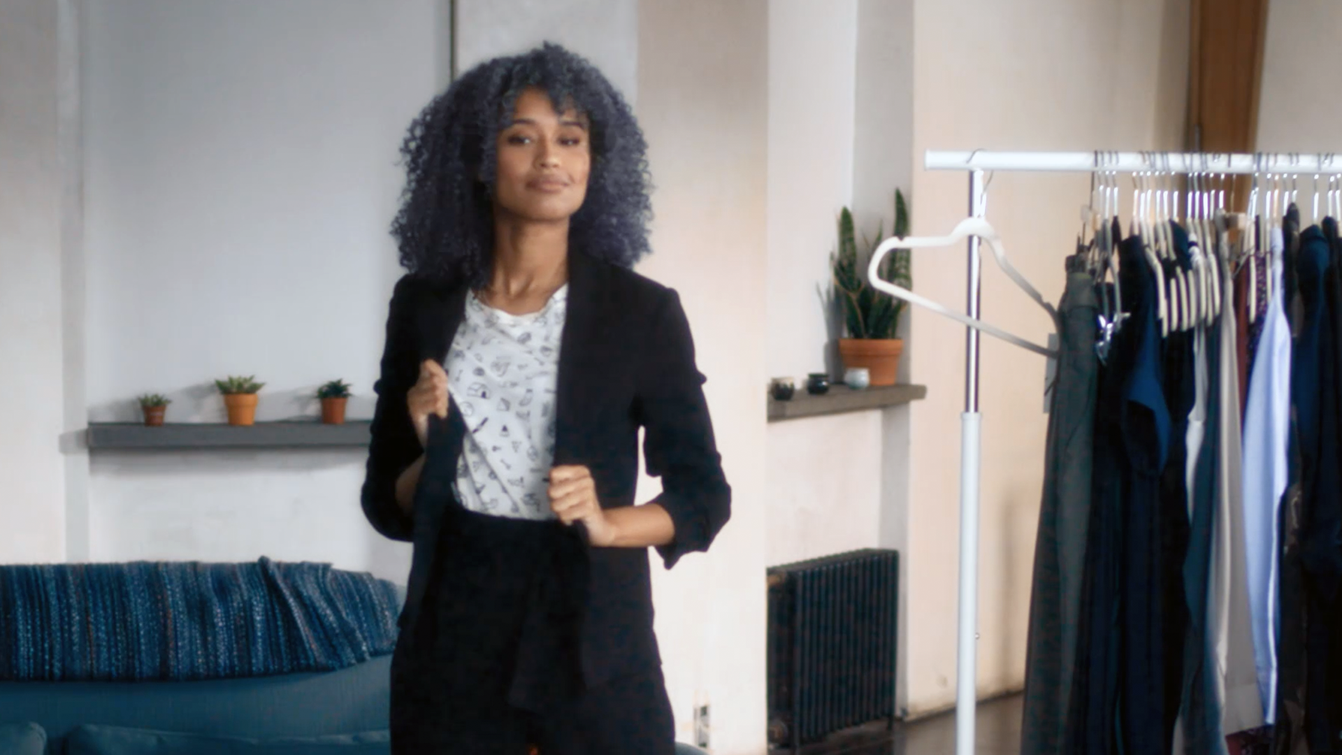 A woman putting on a black blazer.