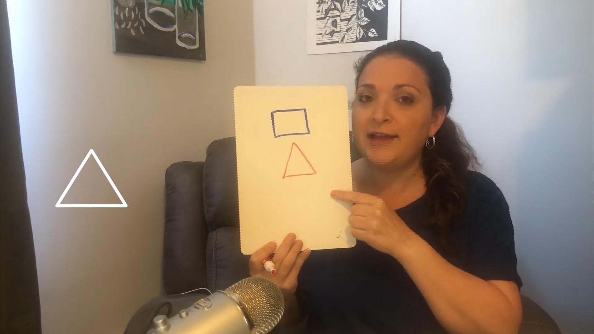 A woman holding a paper with different shapes on it.