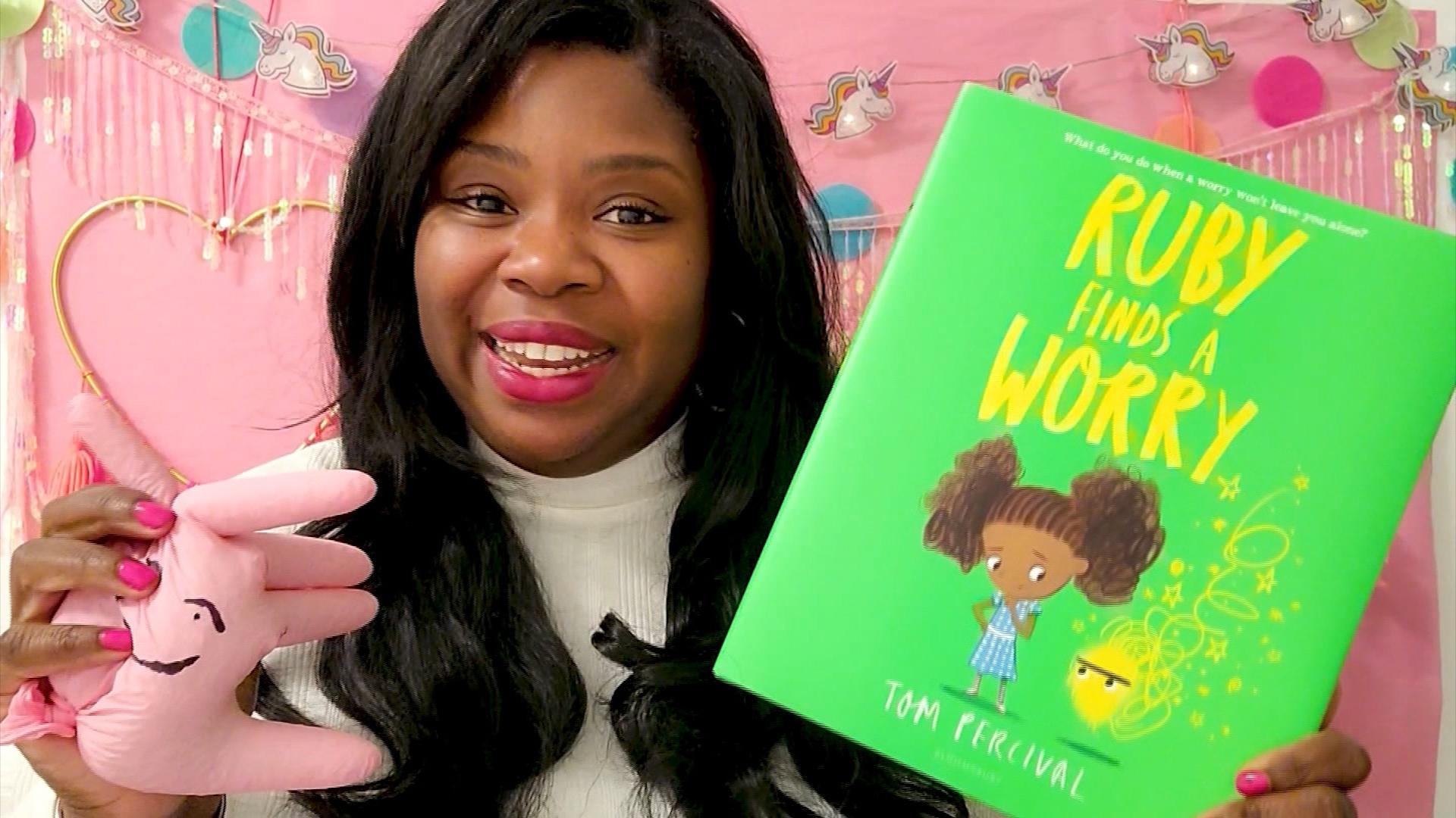 A woman holding a stress reliever and a book titled "Ruby Finds a Worry".