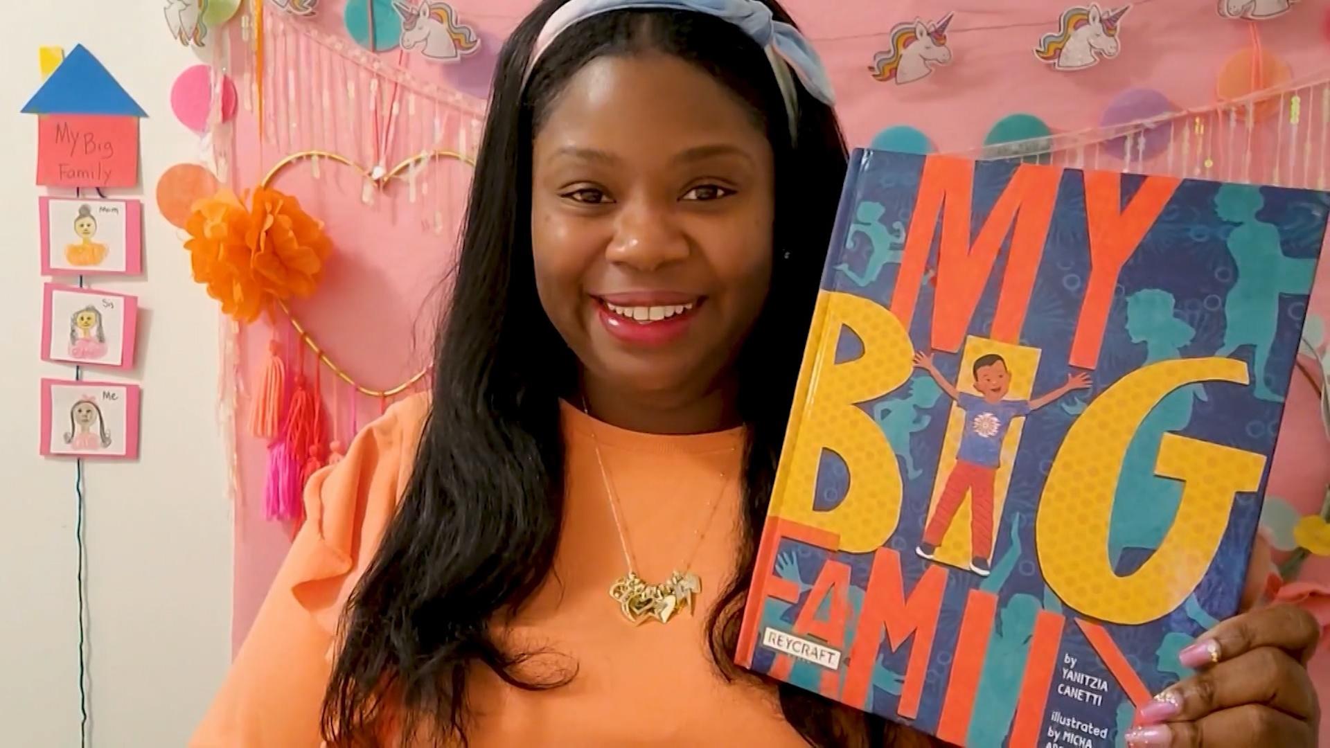 A woman holding up the book "My Big Family".