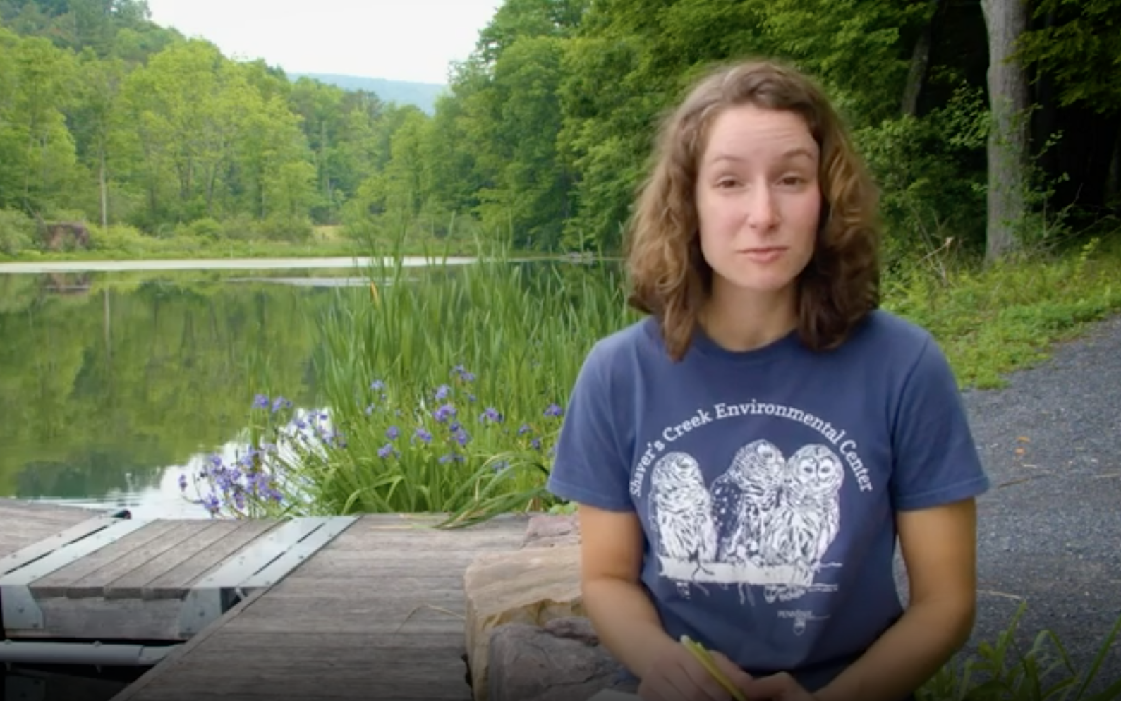 A woman talking in front of a pond.