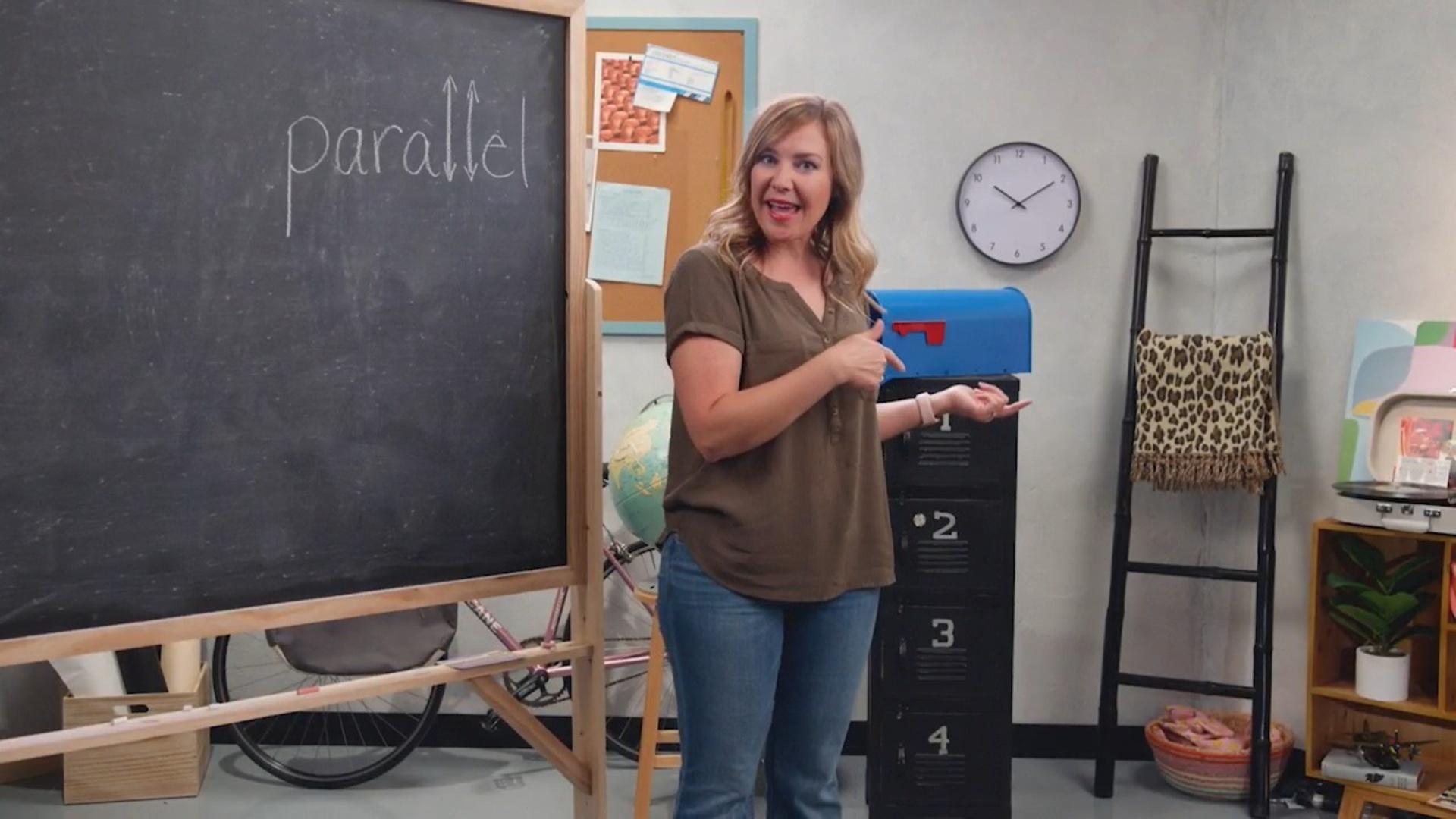 A woman standing in front of a blackboard pointing.