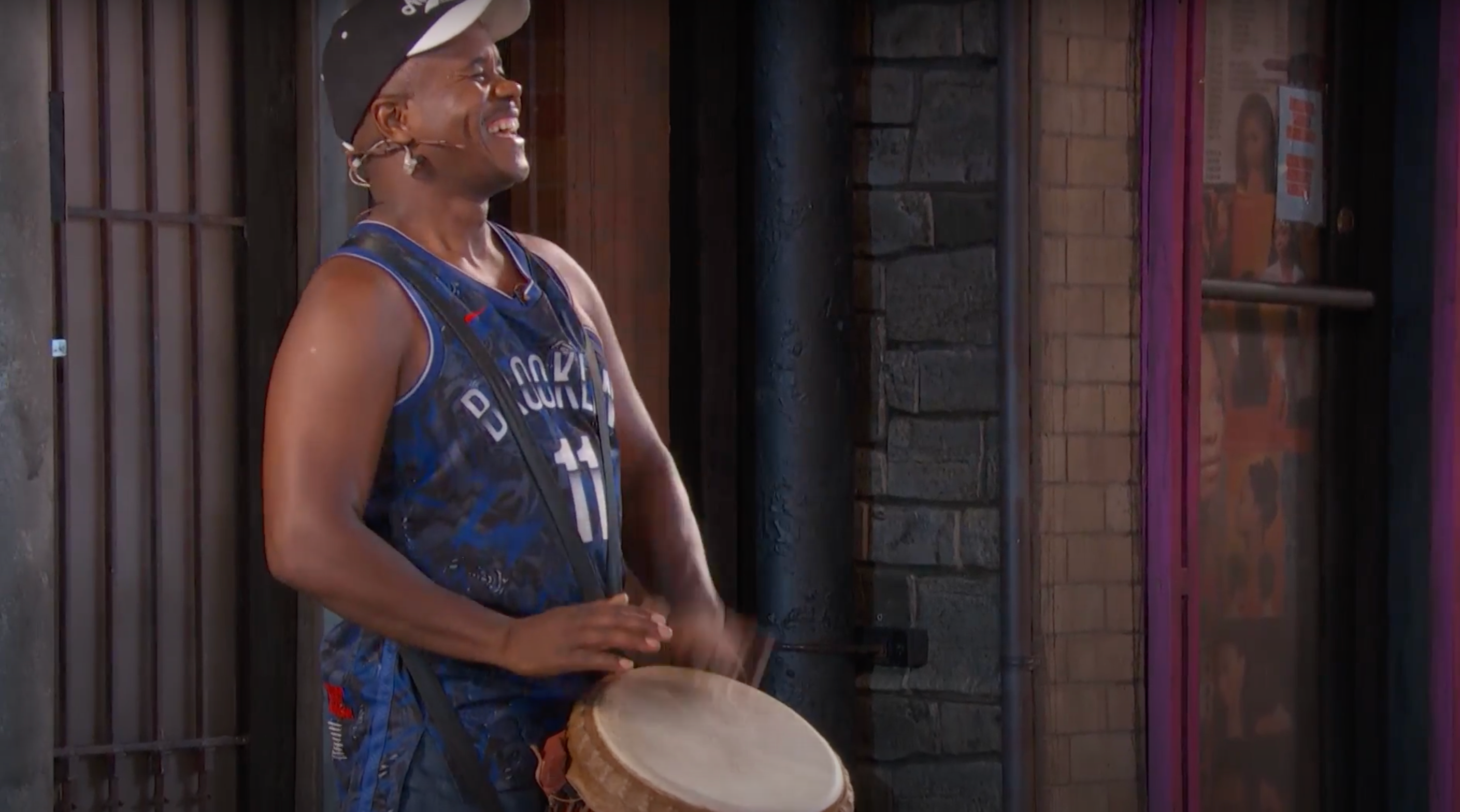 An actor beating a djembe drum on a stage.