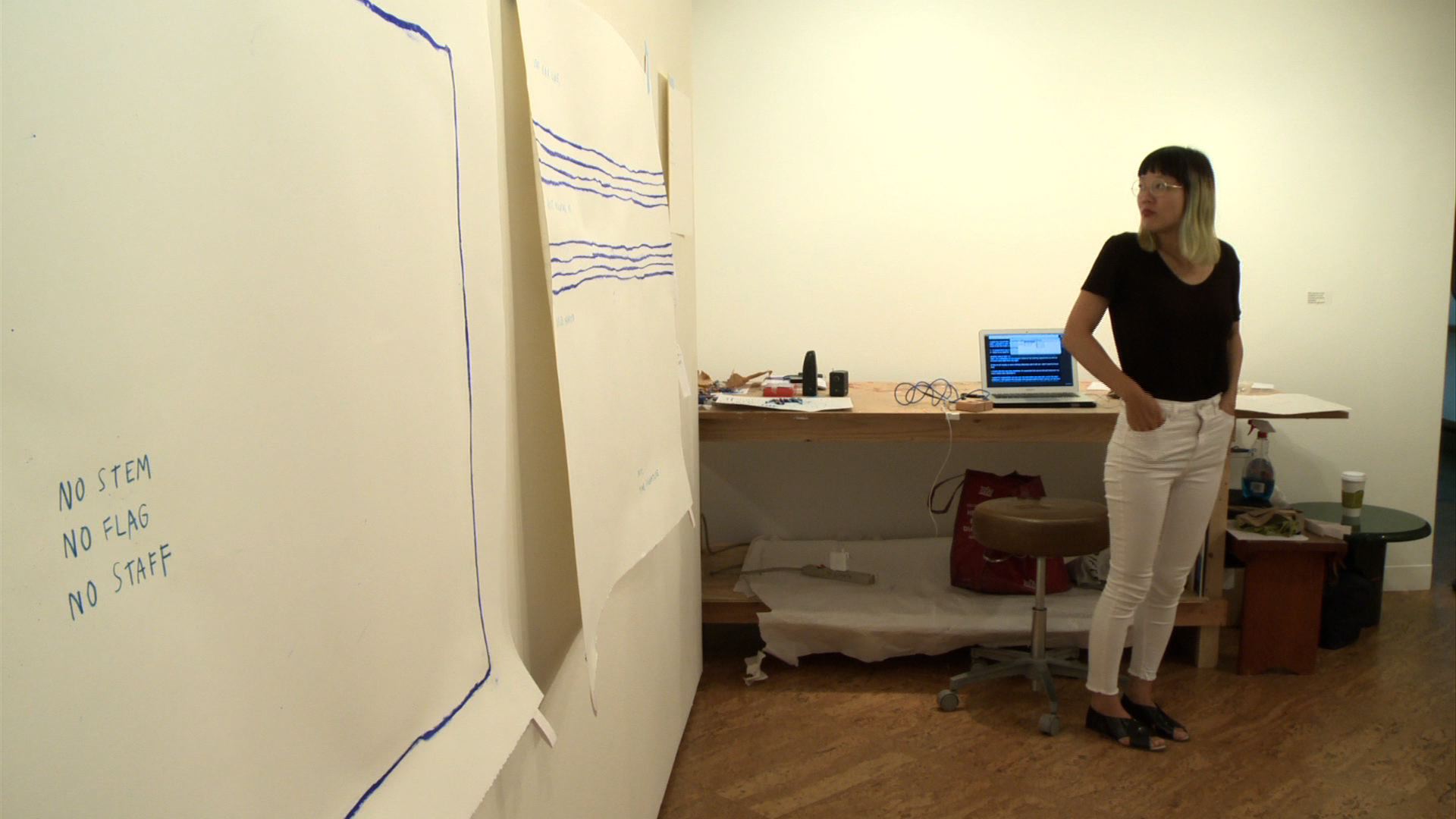 A woman standing in front of a paper with a music staff on it.