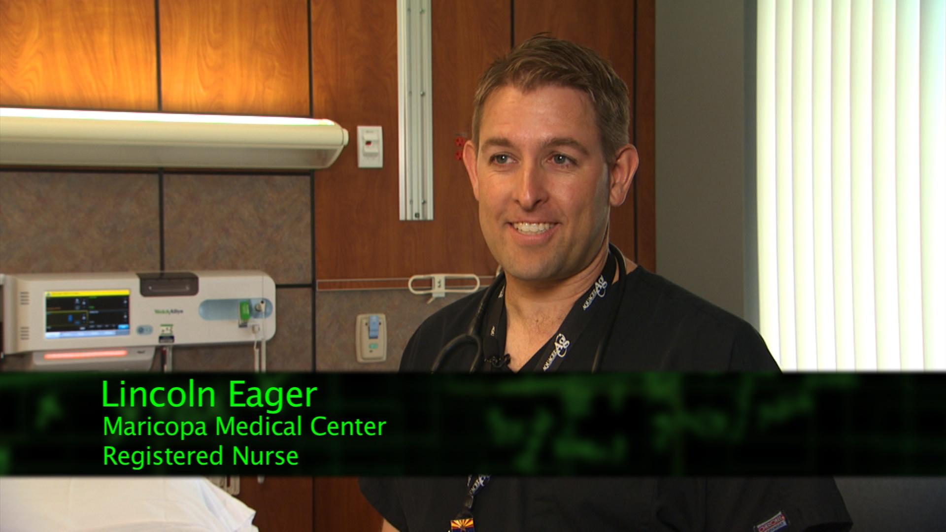 A man in scrubs in front of a hospital room.