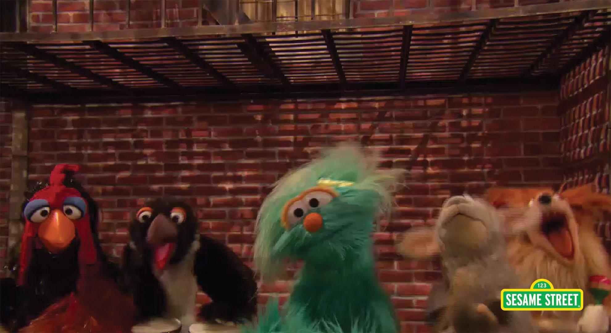 Several puppets stand in front of a brick wall.