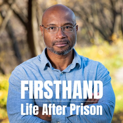 A man in a blue shirt stands with his arms crossed.