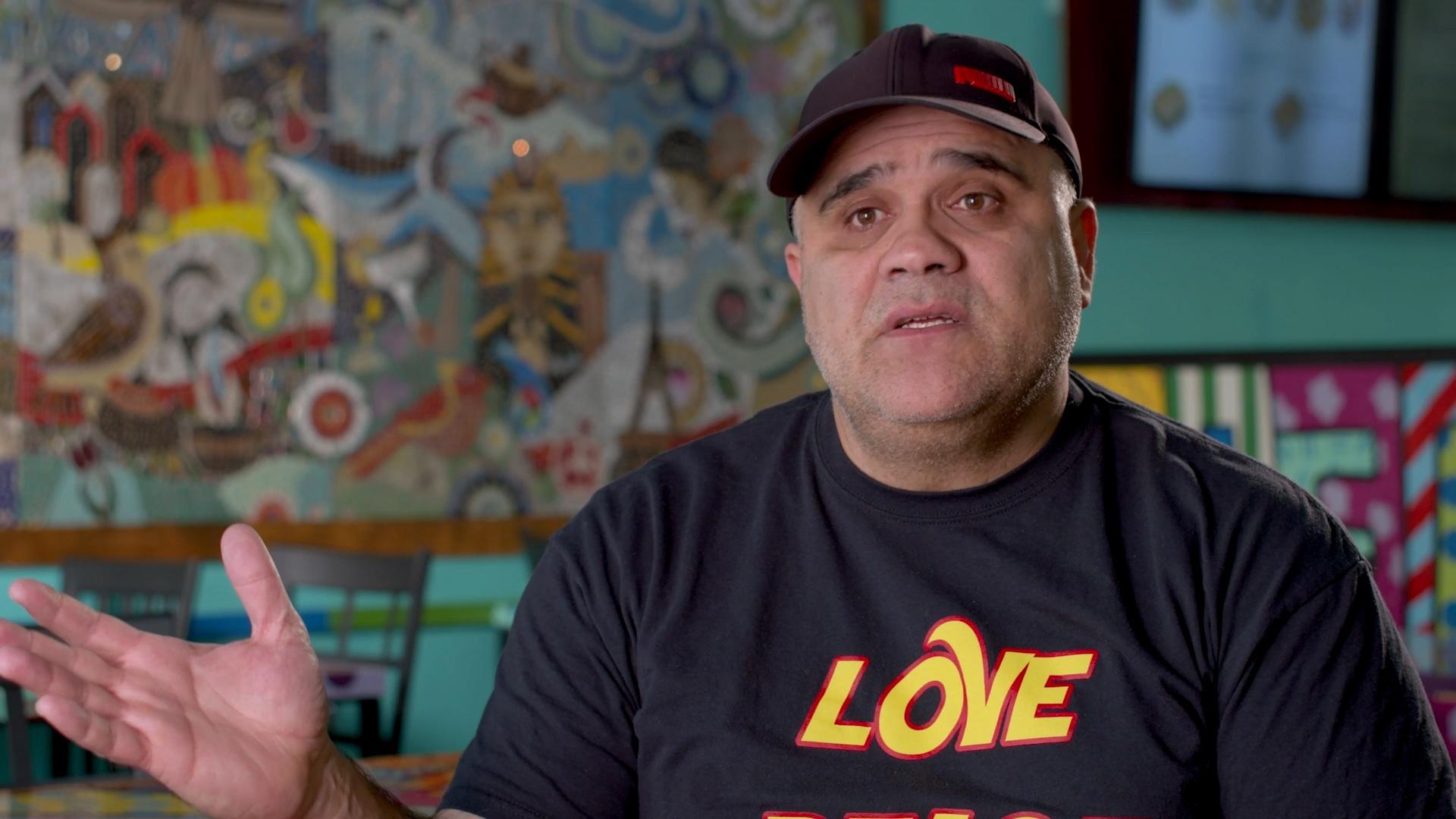 Man wearing a black hat and black t-shirt with the word LOVE.