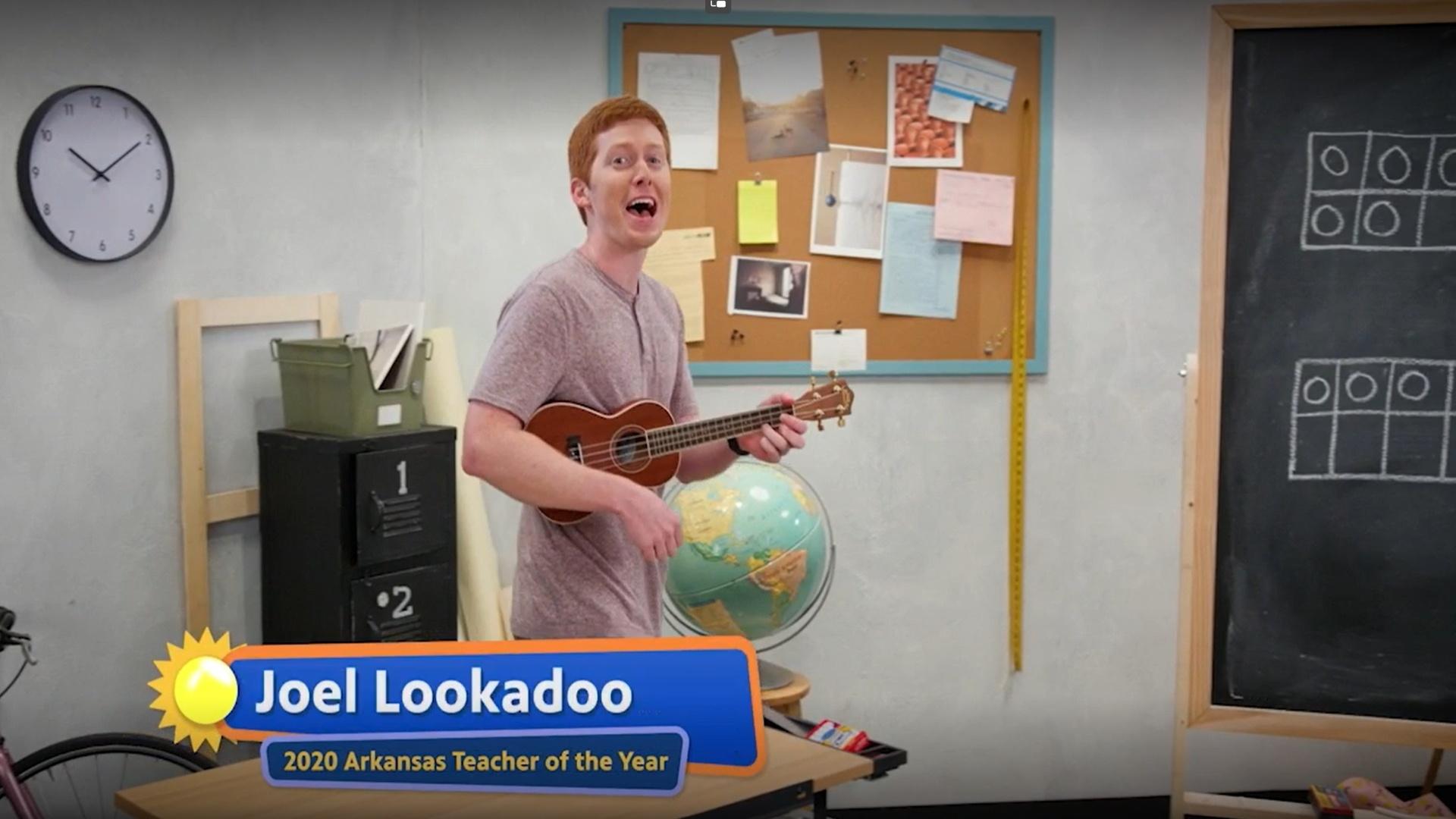 A man in a pink shirt sings and plays the ukelele.