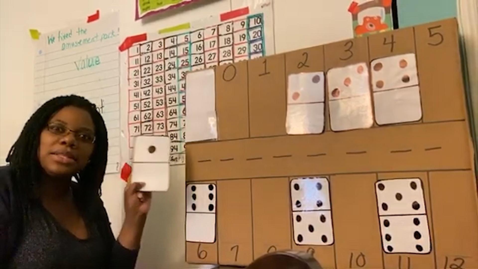 A woman holds up a large domino in front of a cardboard poster.