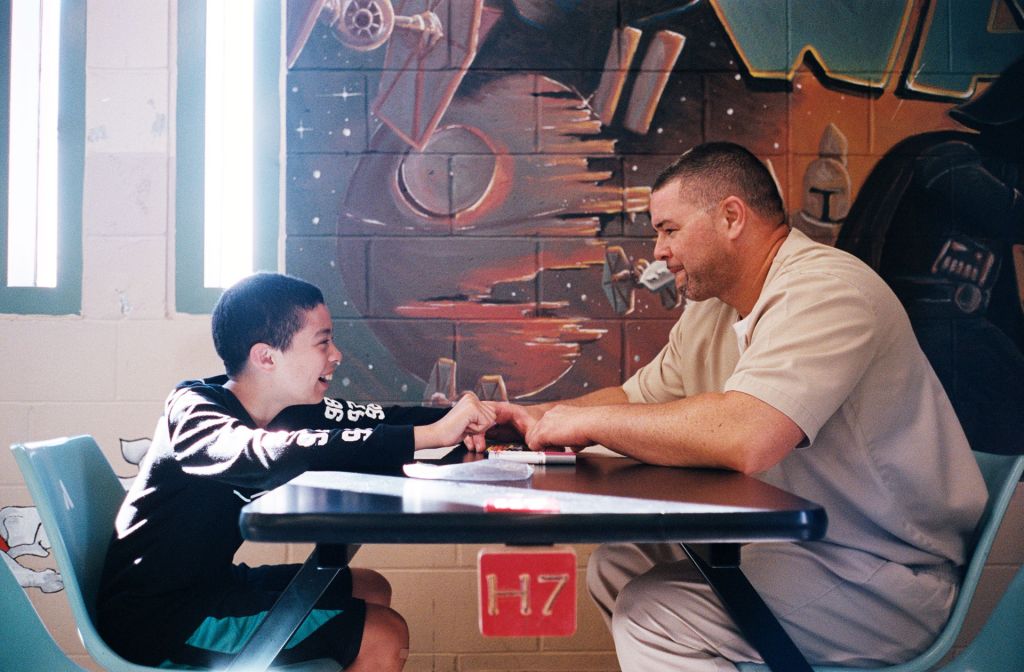 A man and a boy sit across a table from each other.
