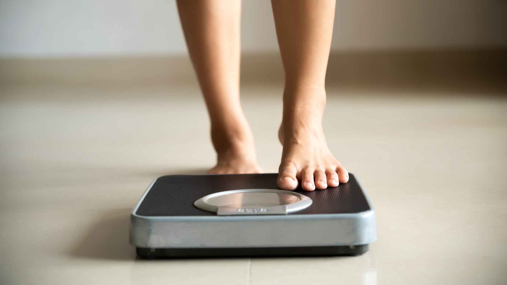 Bare feet stepping on a scale.