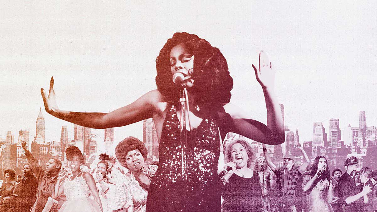 woman in sparkling dress singing into microphone with hands in the air.