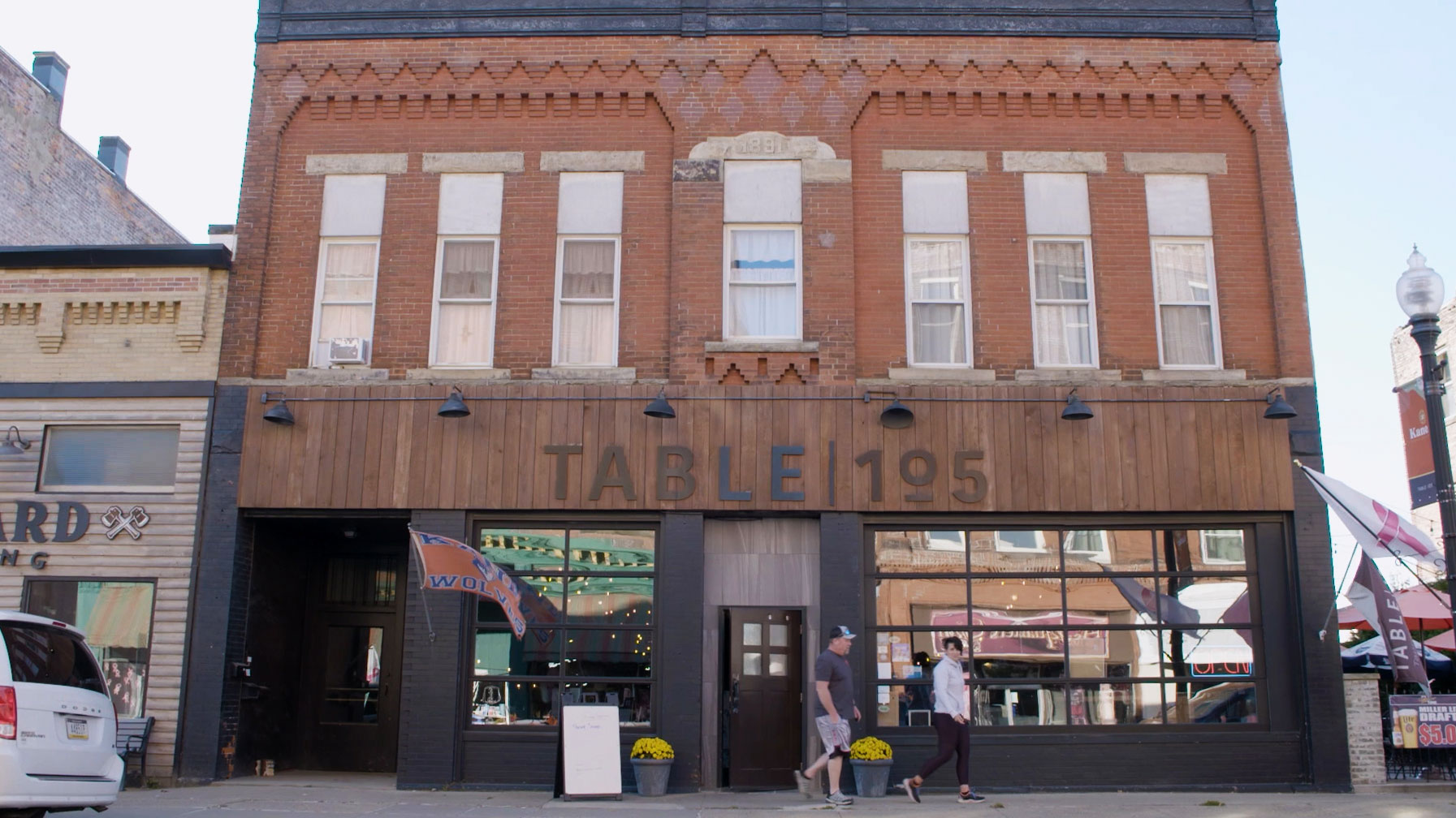 Red brick building with sign reading Table 105 above a black front door.