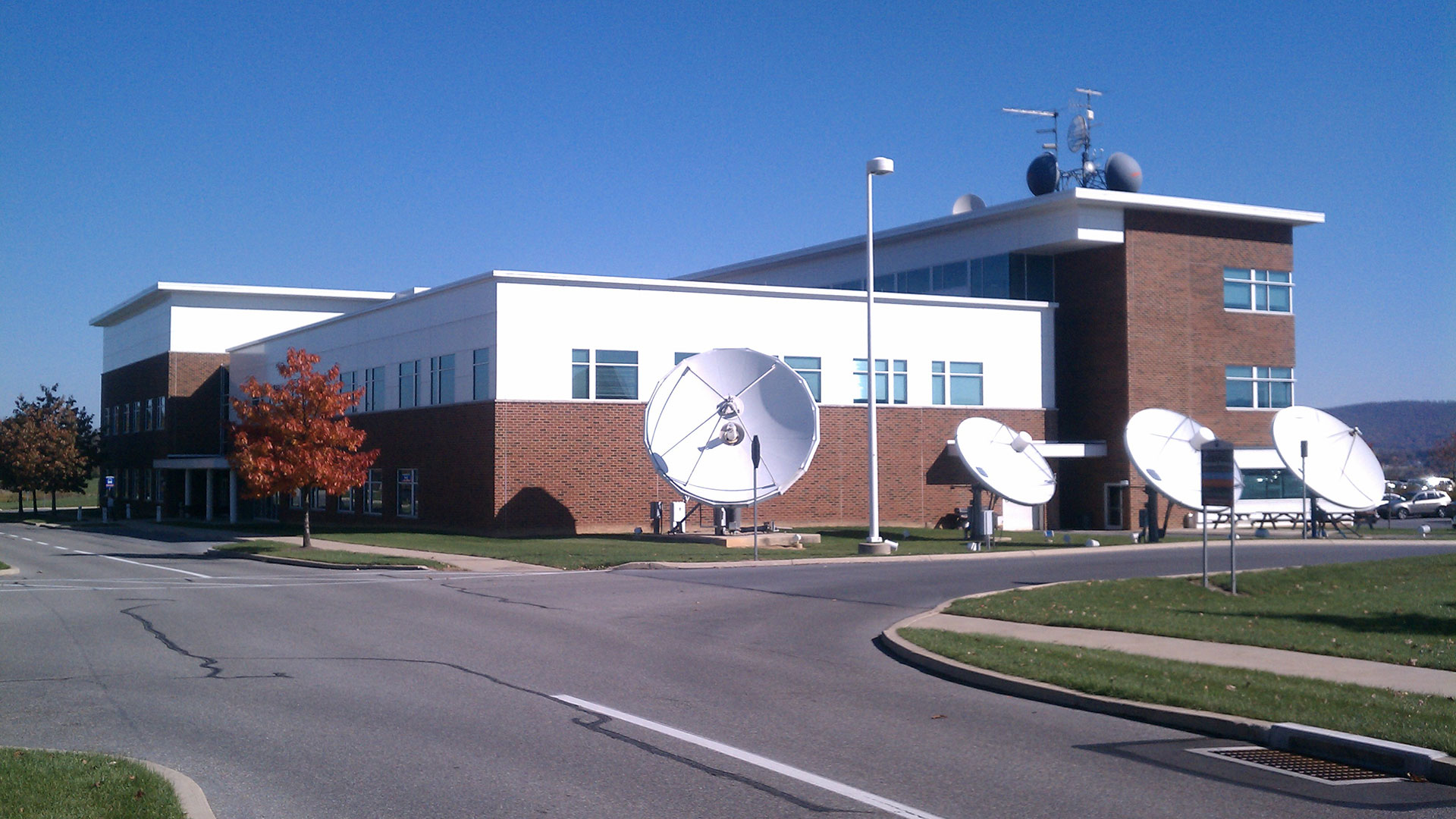 Exterior photo of red brick building with white roof and satellite dishes.