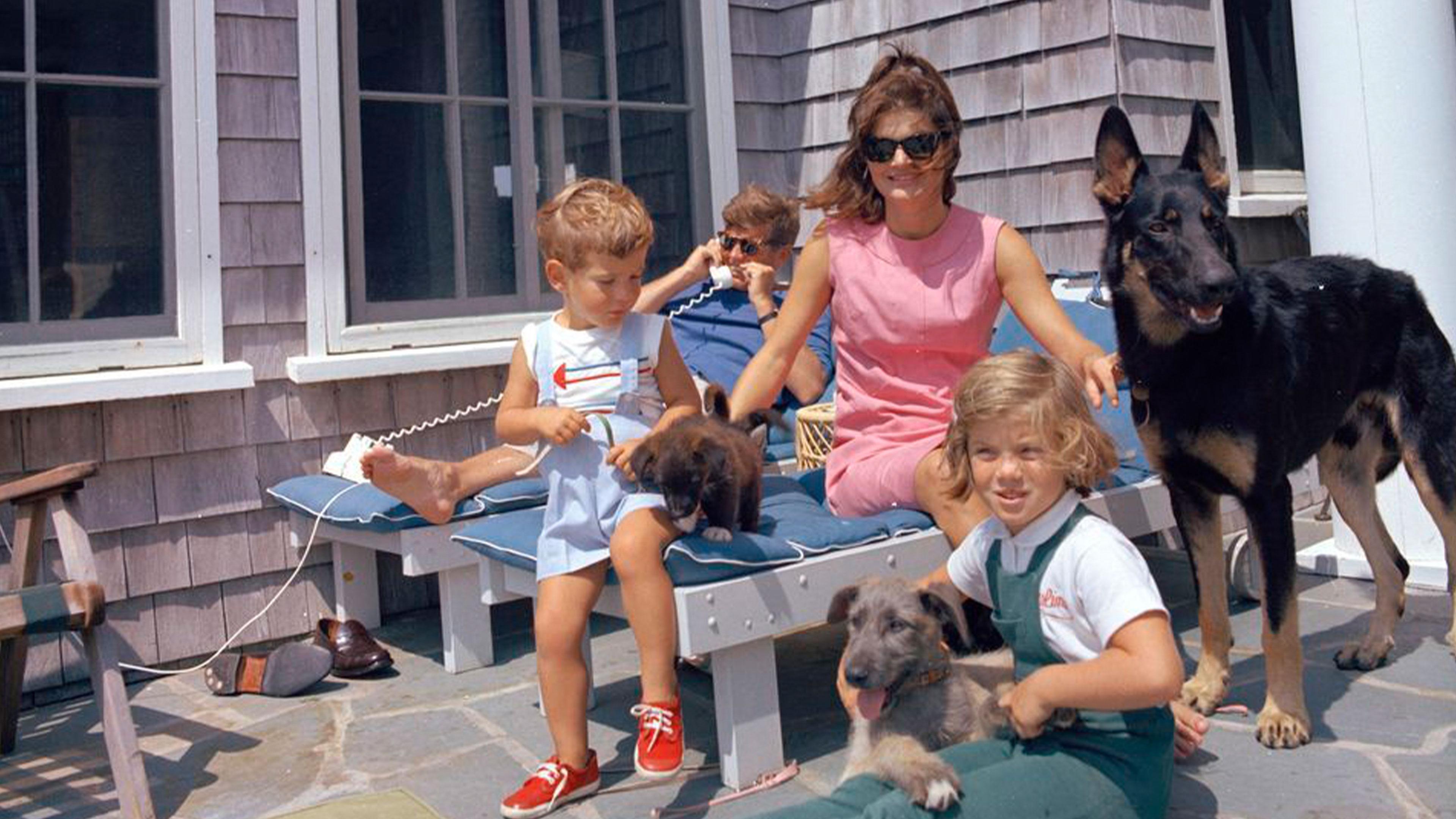 John F Kennedy and Jackie Onassis relaxing with their two children and three dogs.