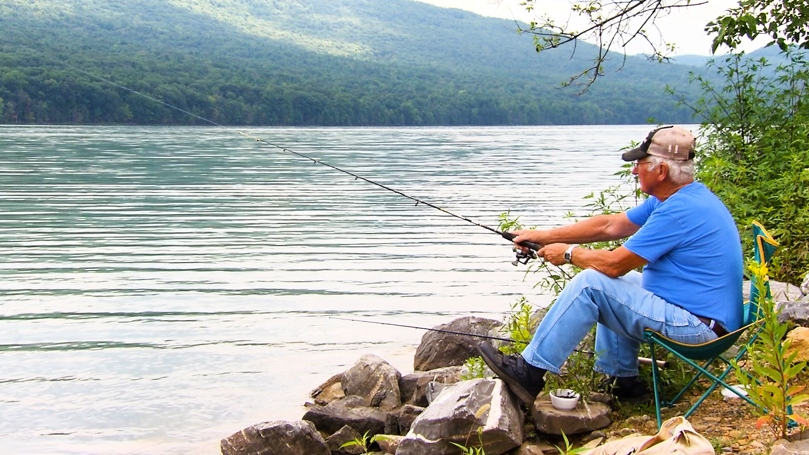 Man fishing on river bank.
