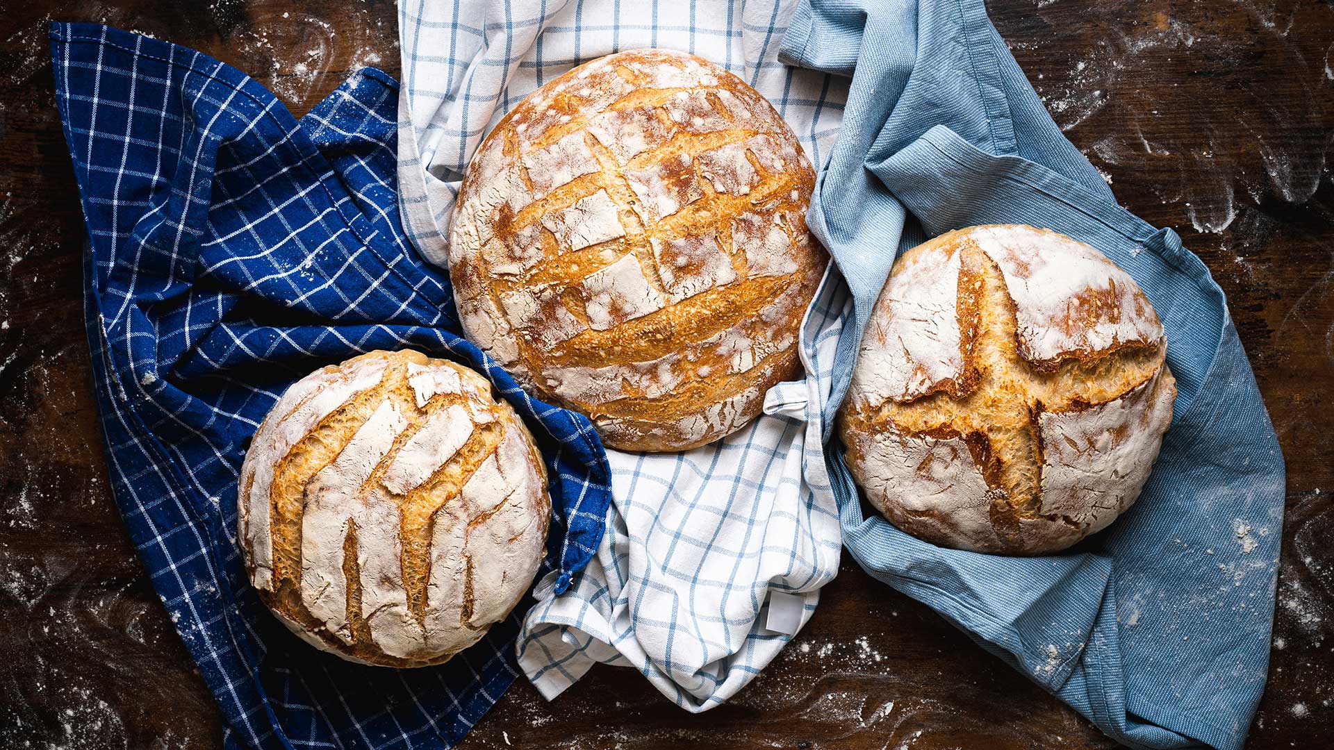 3 loaves of sourdough bread resting on baking cloths.
