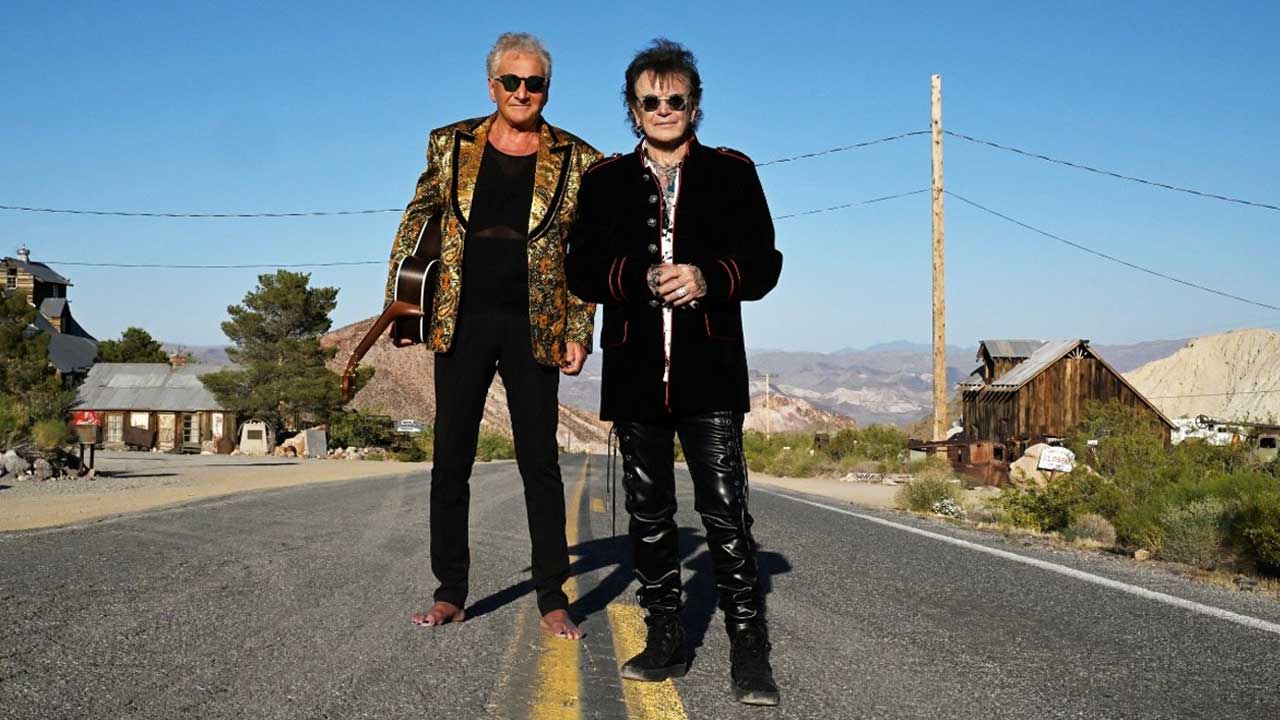 Two members of the band Air Supply standing in the middle of a country road.