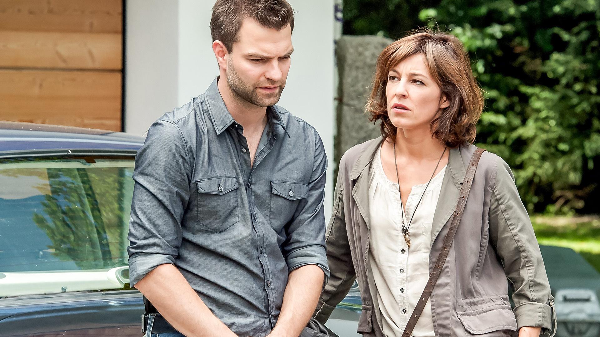 Man on woman talking while leaning against side of a car.