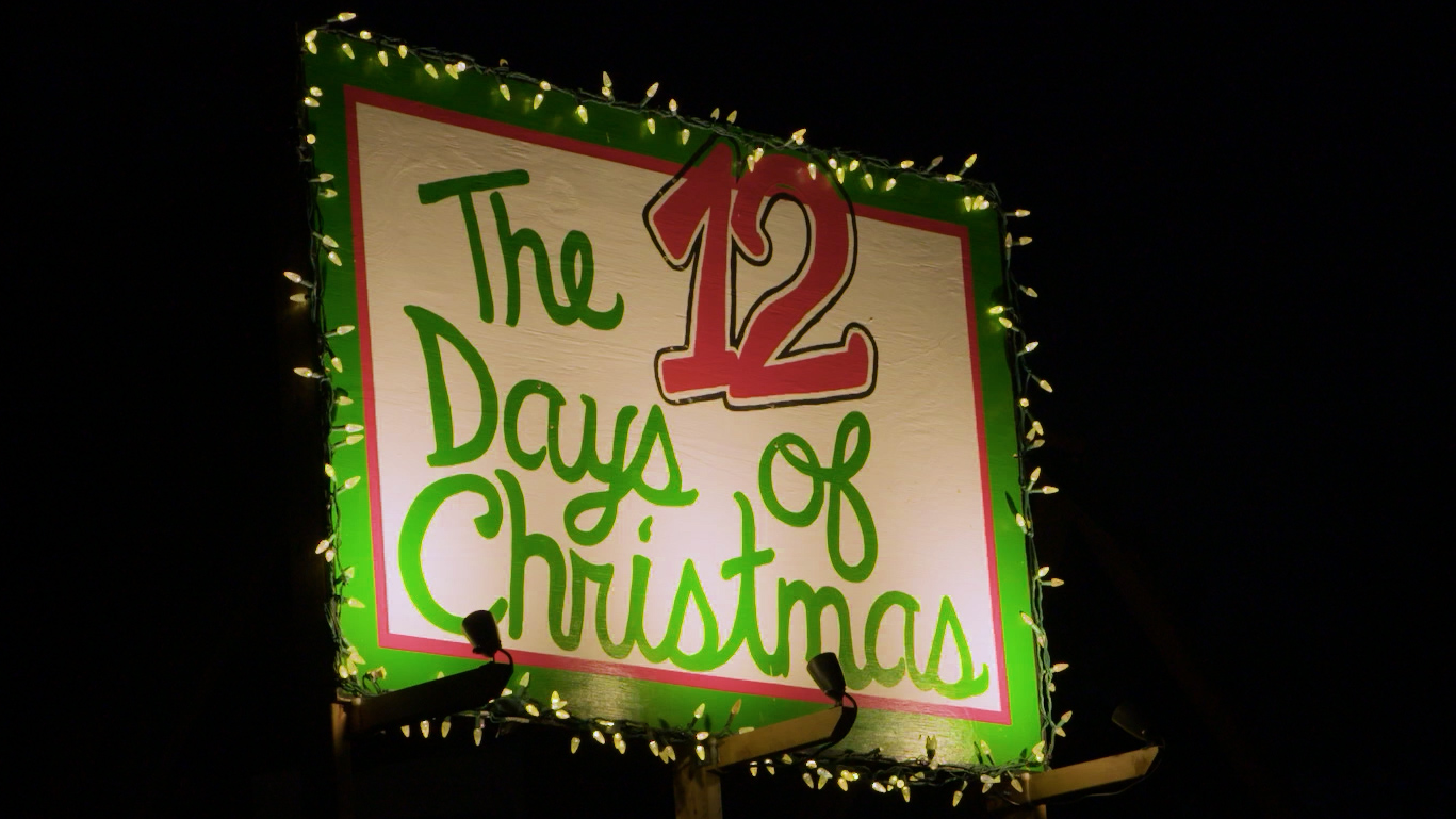 An illuminated yard sign that says "The 12 Days of Christmas"