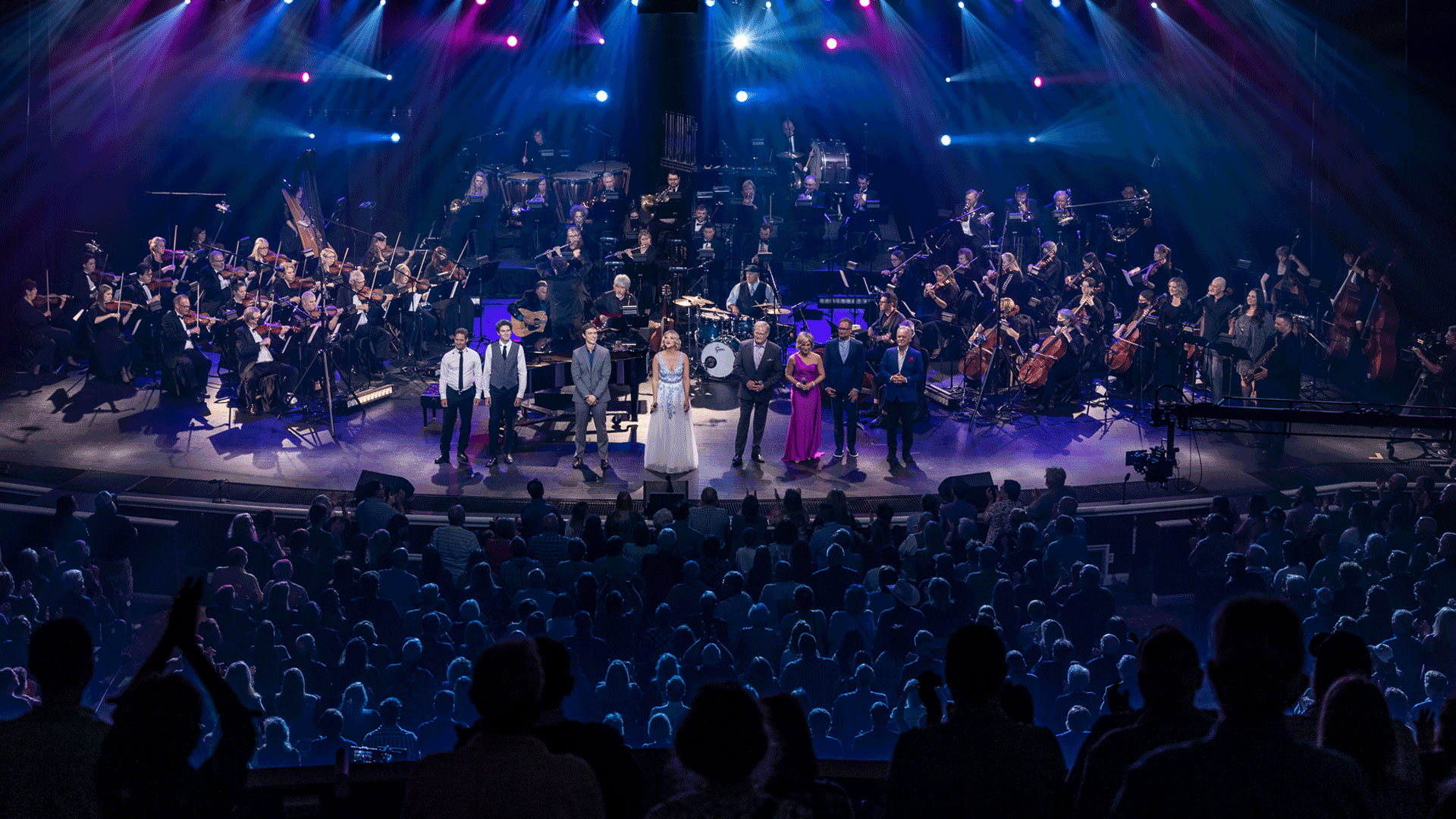 Wide shot of an orchestra on stage in a theater.