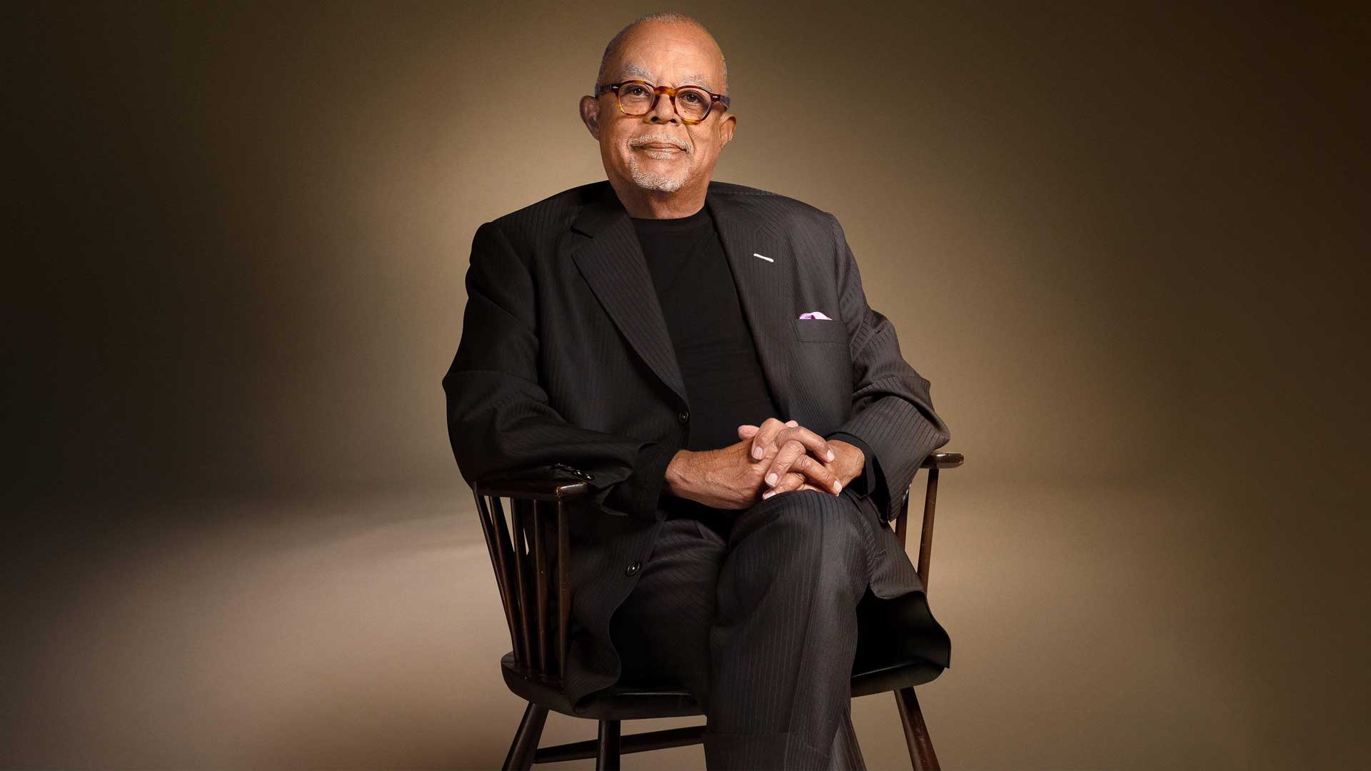 Henry Louis Gates Jr sitting in a chair.