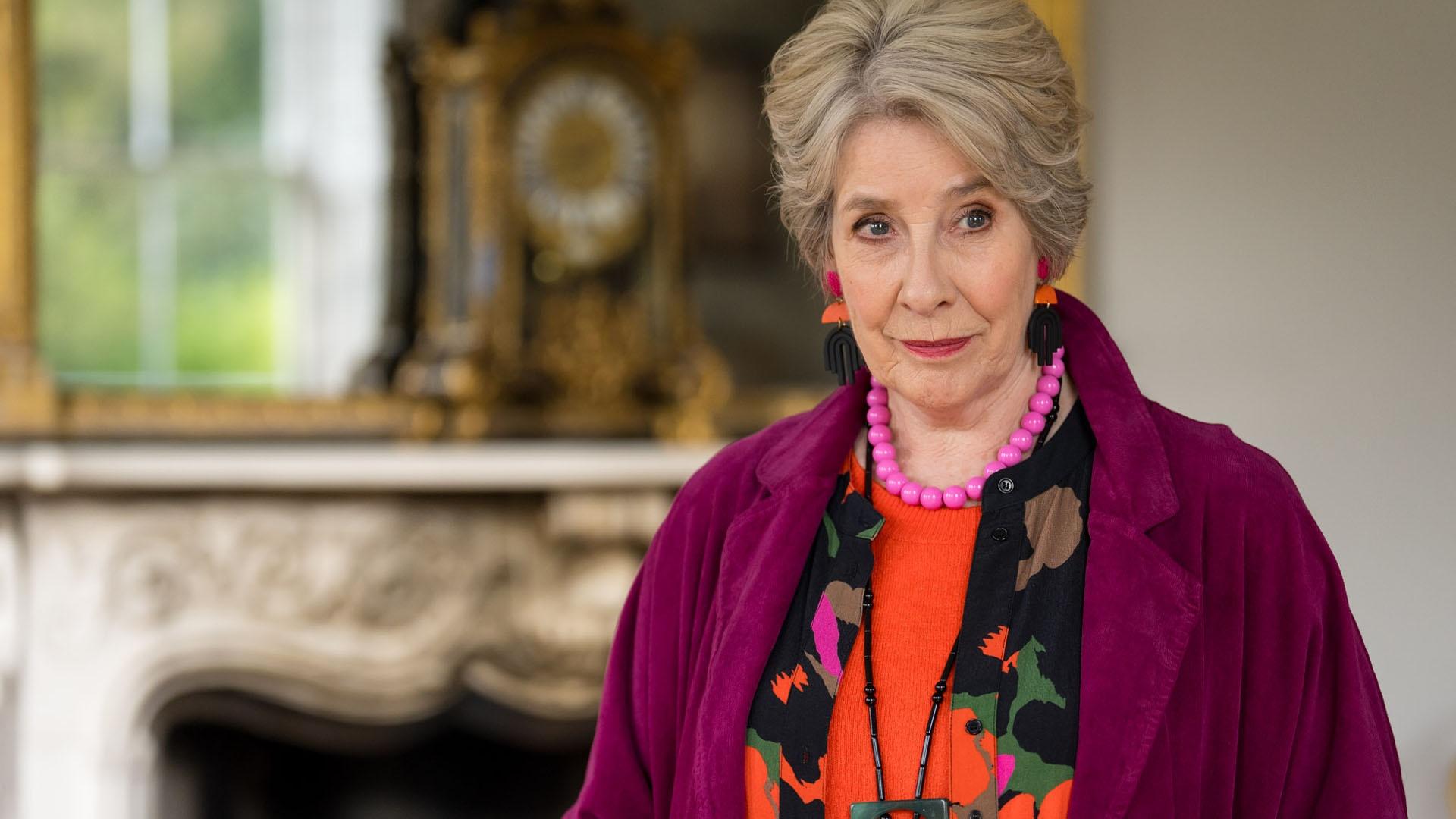 Older woman with short gray hair in a purple coat.