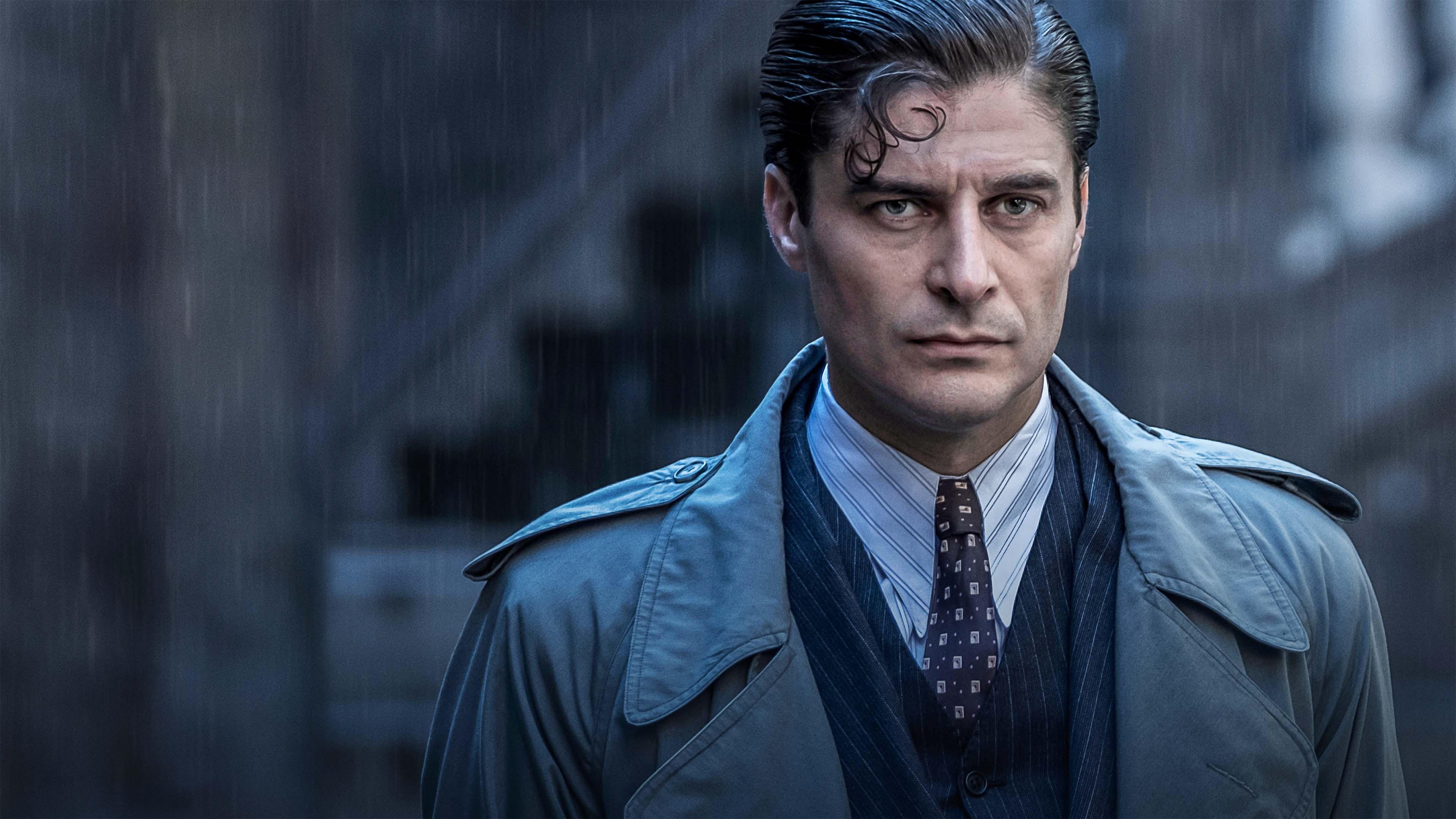 Man in a trench coat standing in the rain.