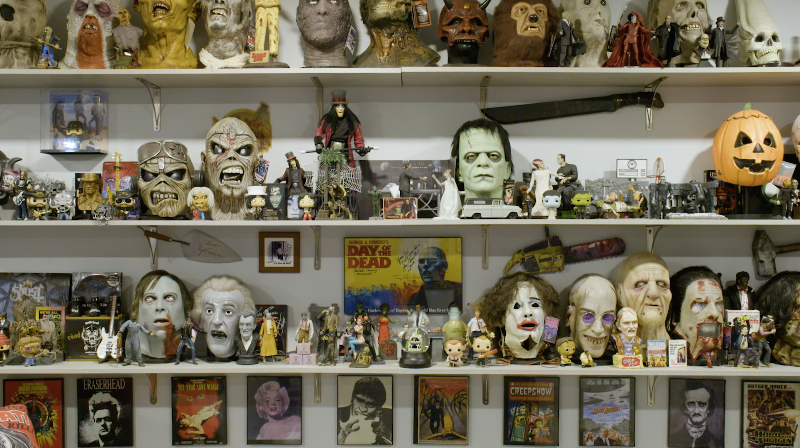 A collection of horror film memorabilia on several shelves.