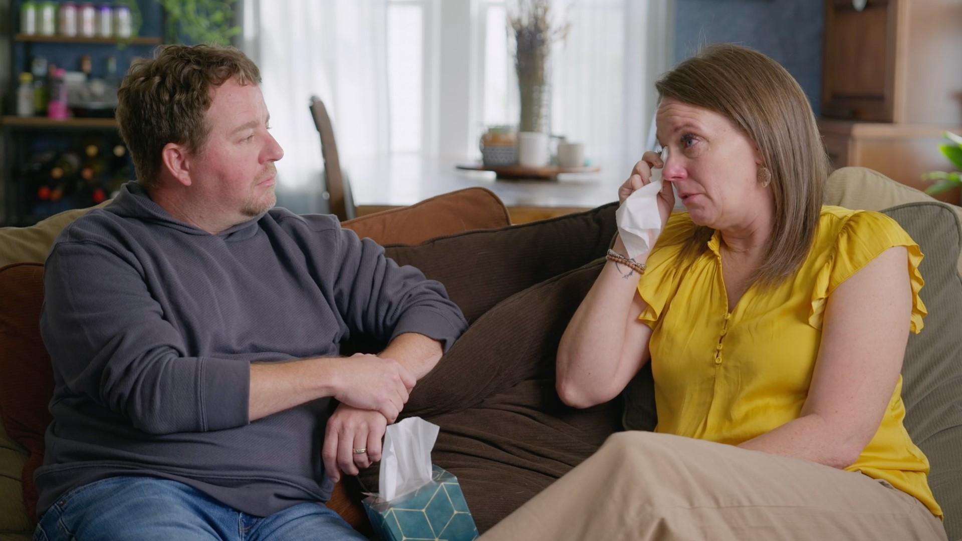 A man and woman sitting on sofa having a tearful conversation.